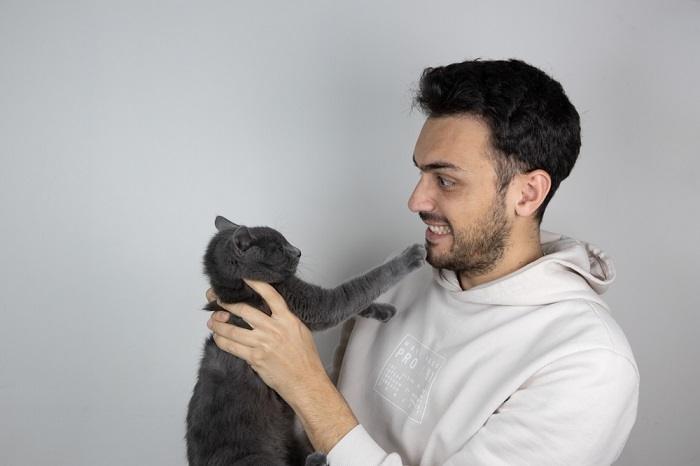 صورة تُظهر رجلاً يتفاعل مع قطة.